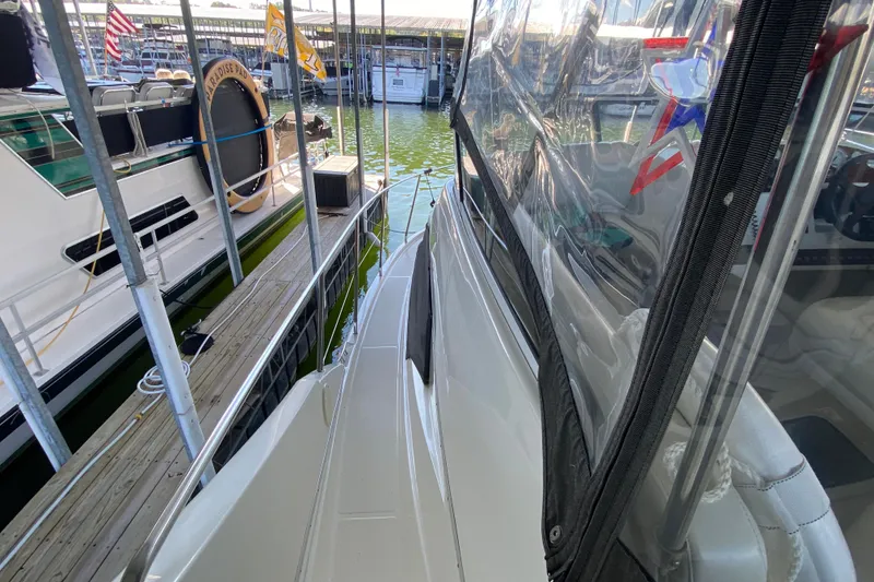 Slide: The Image of 2002 Silverton 330 Sport Bridge docked, featuring sleek design and clear enclosure. - 11
