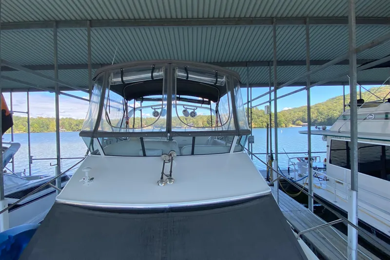 Slide: The Image of 2002 Silverton 330 Sport Bridge docked under a covered marina with scenic lake view. - 14