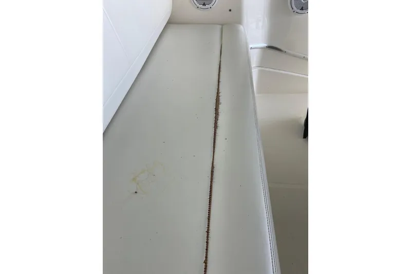 Slide: The Image of 2002 Silverton 330 Sport Bridge interior with worn white seating and visible seam damage. - 27