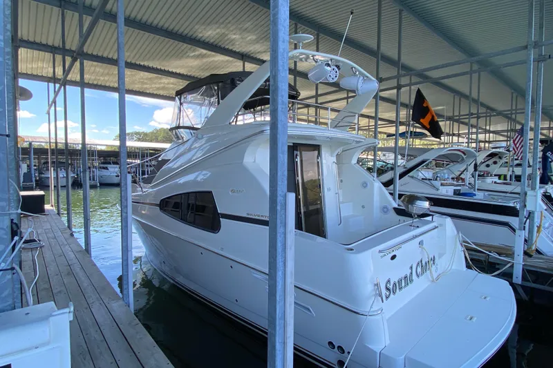Slide: The Image of 2002 Silverton 330 Sport Bridge yacht docked in a marina under a covered shelter. - 3