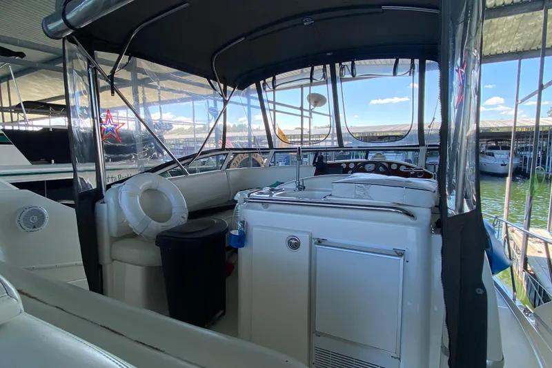 Slide: The Image of 2002 Silverton 330 Sport Bridge interior with helm, seating, and life preserver under canopy. - 7