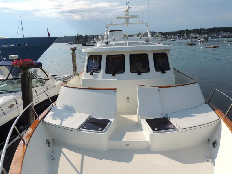 Slide: The Image of 1999 Lyman-Morse pilothouse yacht docked in a scenic marina setting. - 15