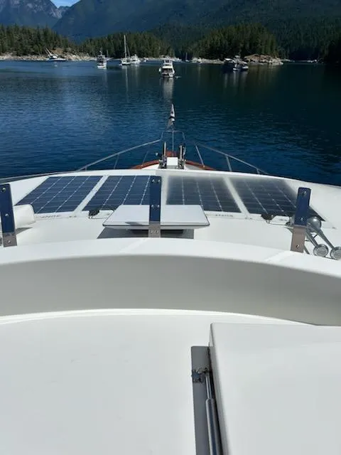 Slide: The Image of 1999 Lyman-Morse pilothouse boat with solar panels, anchored in a scenic bay. - 19