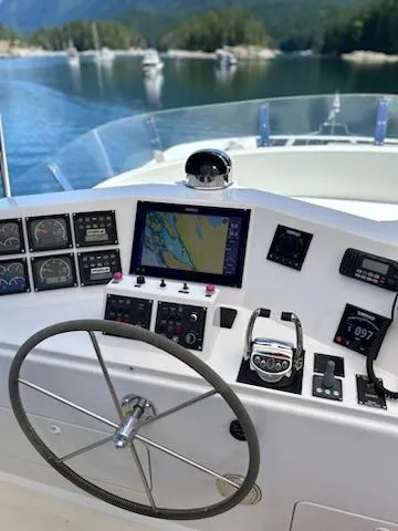 Slide: The Image of 1999 Lyman-Morse pilothouse helm with navigation instruments, steering wheel, and scenic water view. - 20