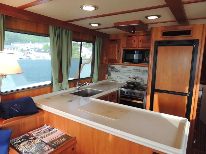 Slide: The Image of 1999 Lyman-Morse pilothouse kitchen with wood cabinetry, sink, stove, and scenic window view. - 26