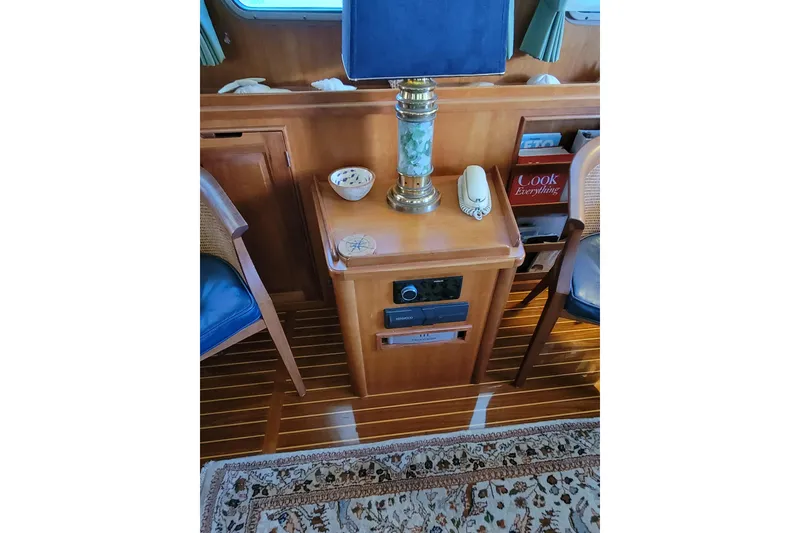Slide: The Image of 1999 Lyman-Morse pilothouse interior with lamp, phone, and books on wooden furniture. - 31