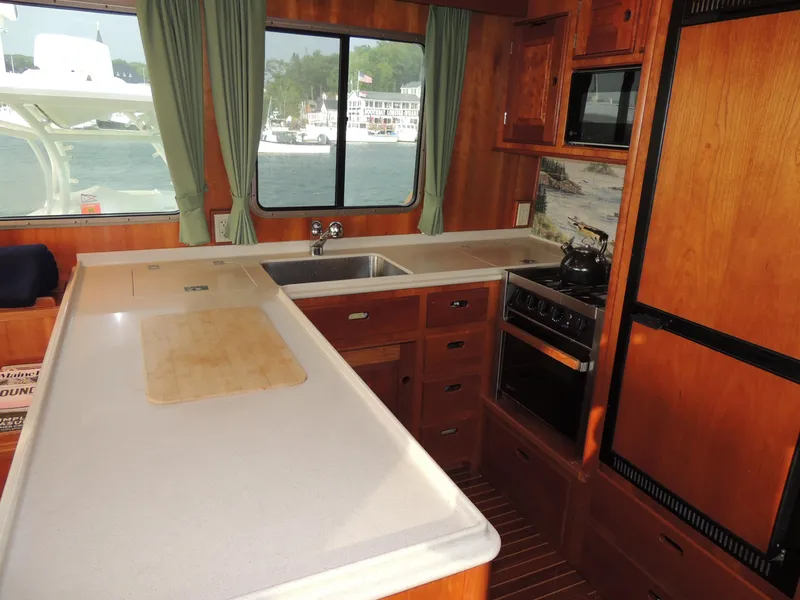 Slide: The Image of 1999 Lyman-Morse pilothouse kitchen with wooden cabinetry, stove, and large windows. - 39