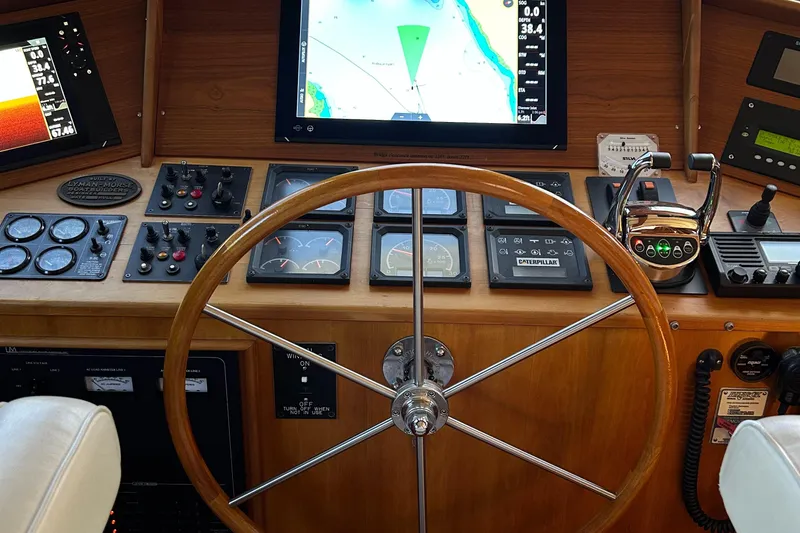 Slide: The Image of Pilothouse helm of 1999 Lyman-Morse boat with navigation instruments and wooden steering wheel. - 42