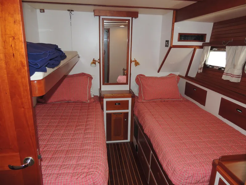 Slide: The Image of 1999 Lyman-Morse pilothouse cabin with twin beds, red checkered bedding, and wooden interior. - 50