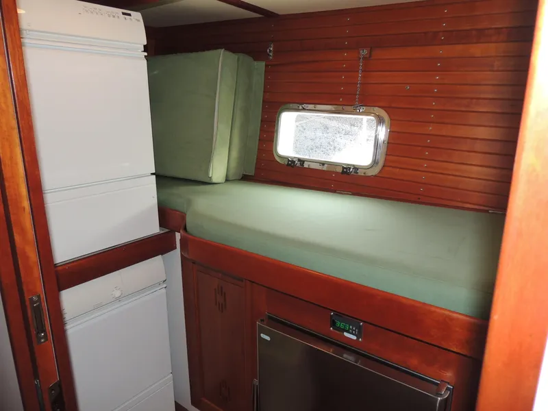 Slide: The Image of 1999 Lyman-Morse pilothouse interior with green cushions, wooden paneling, and compact appliances. - 52