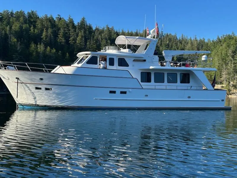 Slide: The Image of 1999 Lyman-Morse pilothouse yacht on serene water, surrounded by lush forest. - 8