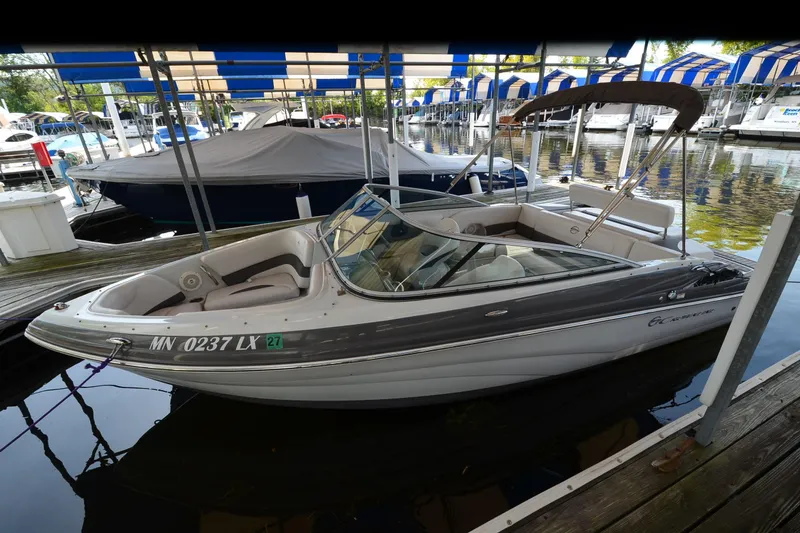 Slide: The Image of 2018 Crownline 205 SS boat docked in a marina with blue-striped canopies. - 17