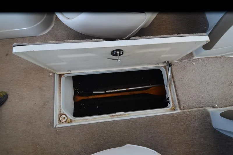 Slide: The Image of Open storage compartment in 2018 Crownline 205 SS boat, revealing interior space and paddle. - 18