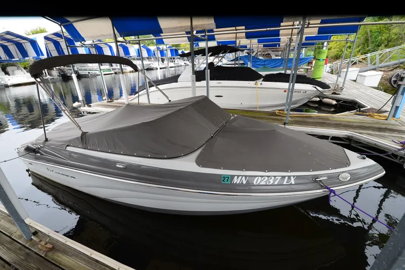Slide: The Image of 2018 Crownline 205 SS boat docked with cover, under blue and white canopy. - 21