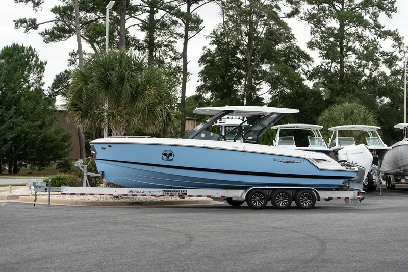 The Image of 2026 Monterey Elite 30 OB boat on trailer, parked outdoors with trees in background. - 0