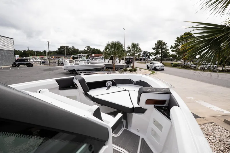 Slide: The Image of 2026 Monterey Elite 30 OB boat with sleek seating, parked outdoors near palm trees. - 27