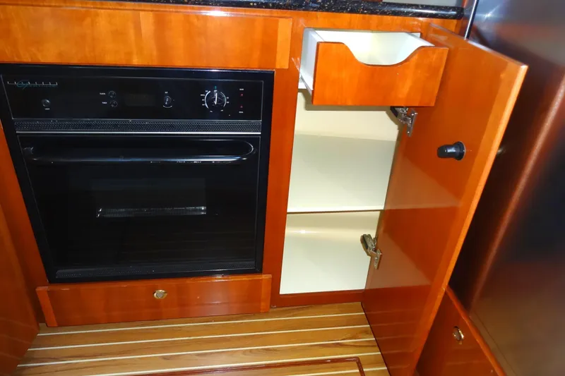 Slide: The Image of 2007 Meridian 459 yacht kitchen with oven, wooden cabinets, and open storage. - 107