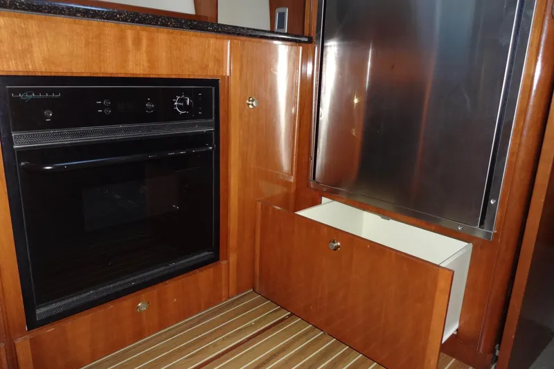 Slide: The Image of 2007 Meridian 459 yacht kitchen with oven, stainless steel fridge, and wooden cabinetry. - 108