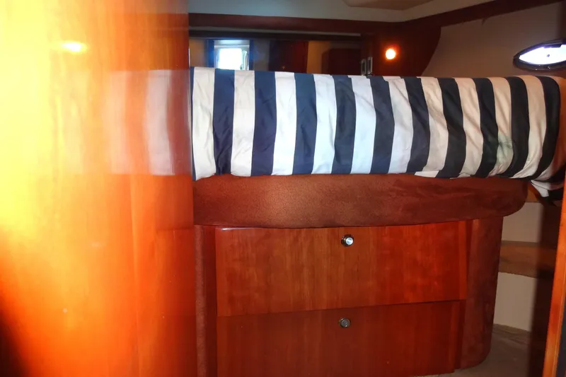 Slide: The Image of Luxurious 2007 Meridian 459 yacht cabin with striped bedding and wooden storage drawers. - 128