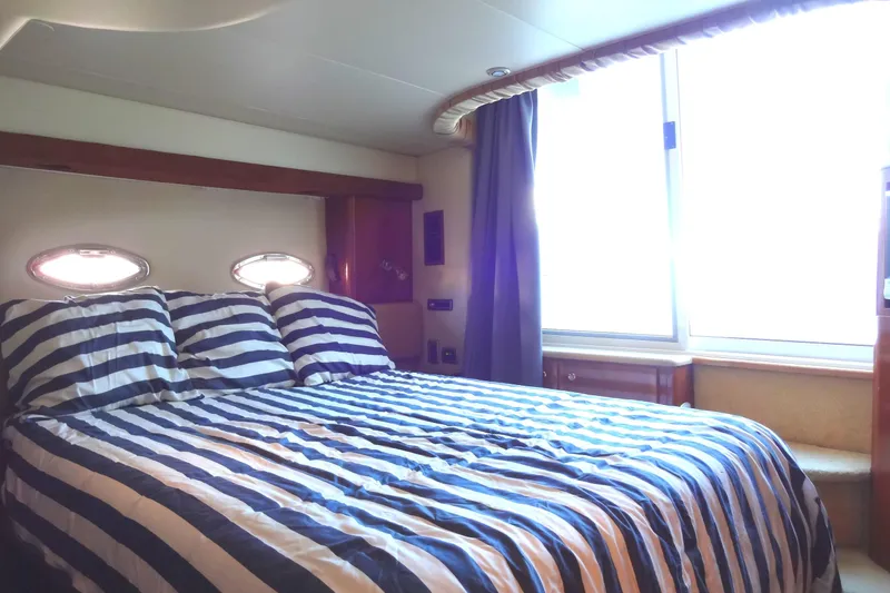 Slide: The Image of Luxurious bedroom in 2007 Meridian 459 yacht with striped bedding and porthole windows. - 135
