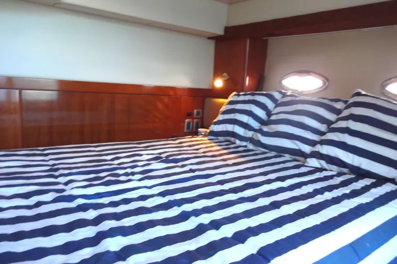 Slide: The Image of Luxurious 2007 Meridian 459 yacht bedroom with striped bedding and wooden accents. - 136