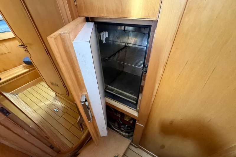 Slide: The Image of 1992 Wauquiez Kronos yacht interior with open wooden cabinet and built-in refrigerator. - 25