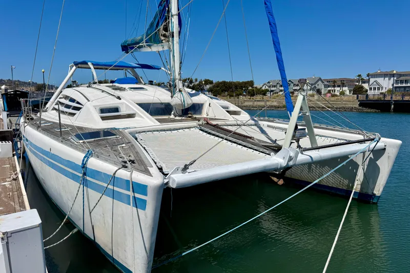 Slide: The Image of 1992 Wauquiez Kronos catamaran docked in a marina under clear blue skies. - 3