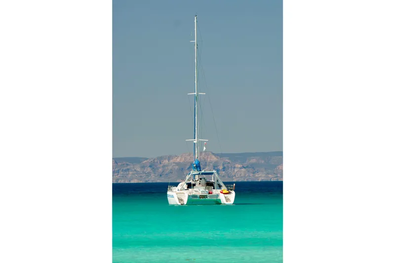 Slide: The Image of Sailing catamaran Wauquiez Kronos 1992 on turquoise sea with mountainous backdrop. - 31