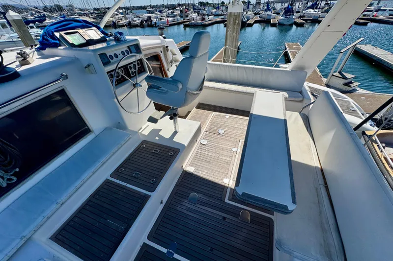Slide: The Image of Cockpit of 1992 Wauquiez Kronos yacht with steering wheel and seating, docked at marina. - 8