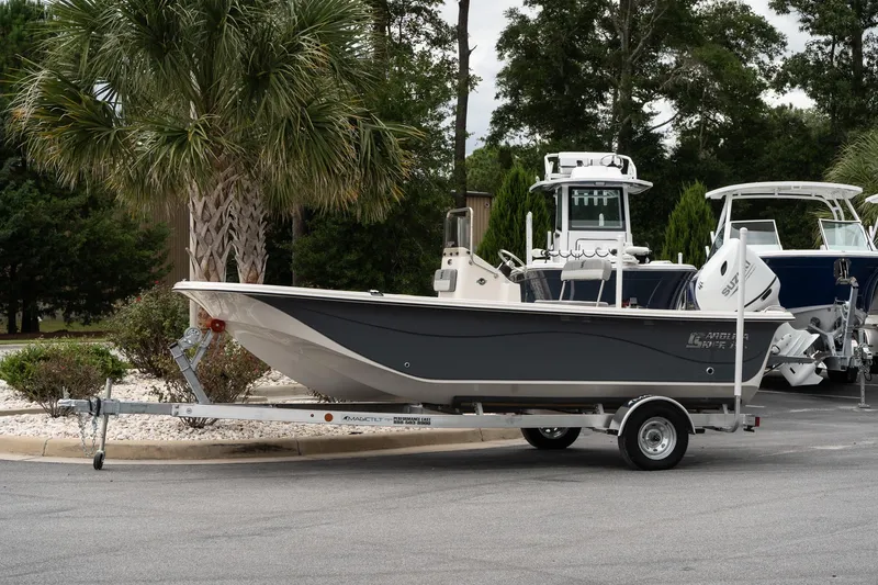 The Image of 2025 Carolina Skiff 19 LS boat on trailer, parked near palm trees. - 1