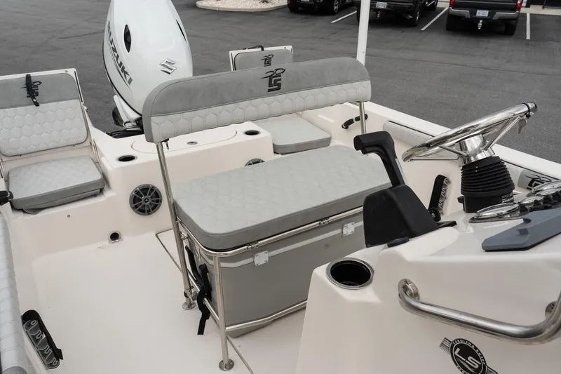 Slide: The Image of 2025 Carolina Skiff 19 LS boat interior with seating, steering wheel, and Suzuki outboard motor. - 13