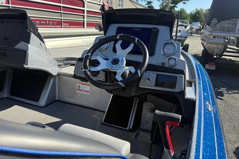 Slide: The Image of 2024 Nitro Z19 Pro boat dashboard with steering wheel and gauges in a marina setting. - 2