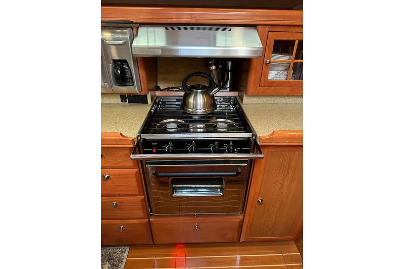 Slide: The Image of 2008 Hunter 49 yacht kitchen with stove, kettle, and wooden cabinetry. - 57