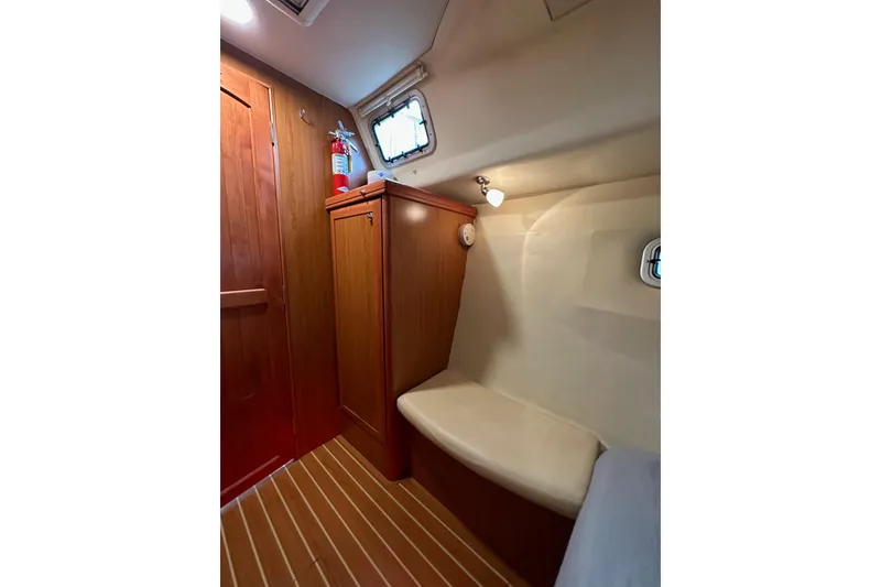 Slide: The Image of 2008 Hunter 49 yacht interior with wooden cabinetry, seating, and a fire extinguisher. - 64