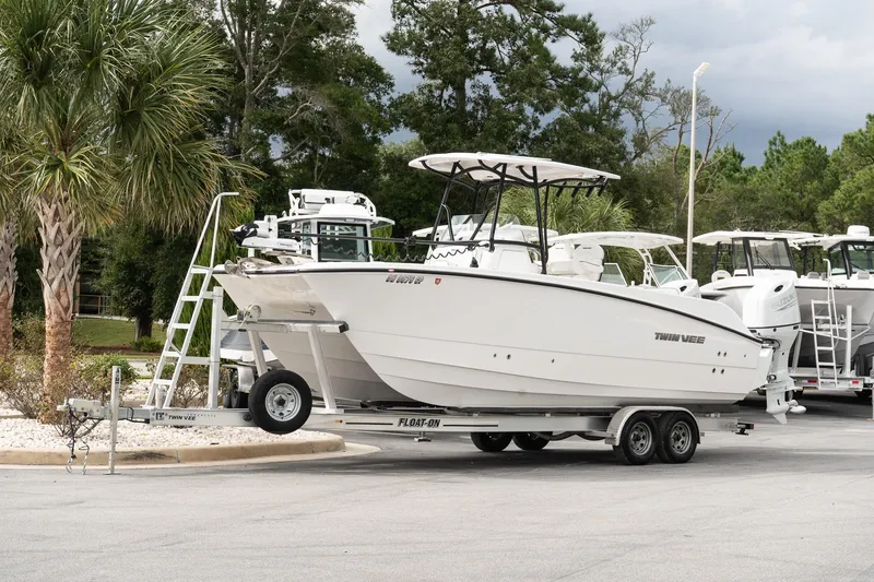 Slide: The Image of 2025 Twin Vee 240 GFX CC boat on trailer, parked near palm trees. - 2