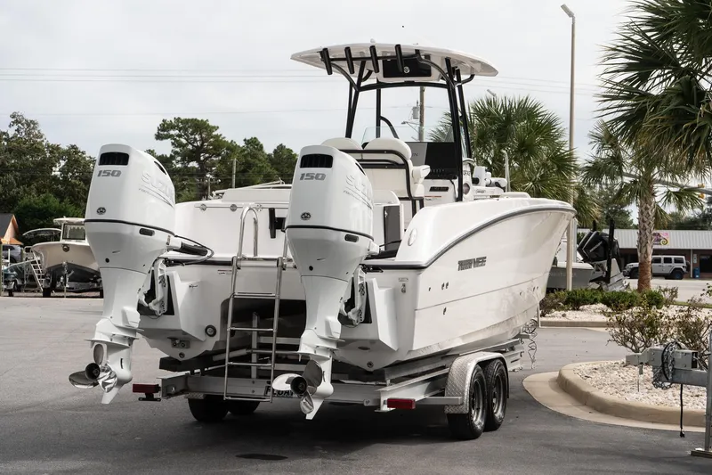 Slide: The Image of 2025 Twin Vee 240 GFX CC boat with dual engines on a trailer, parked outdoors. - 6
