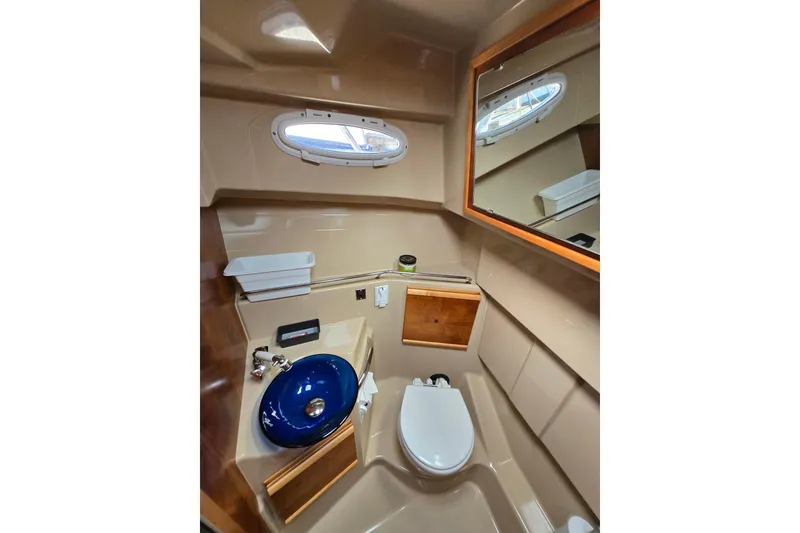 Slide: The Image of 2015 Cutwater C28 boat bathroom with blue sink, toilet, and mirror. - 14