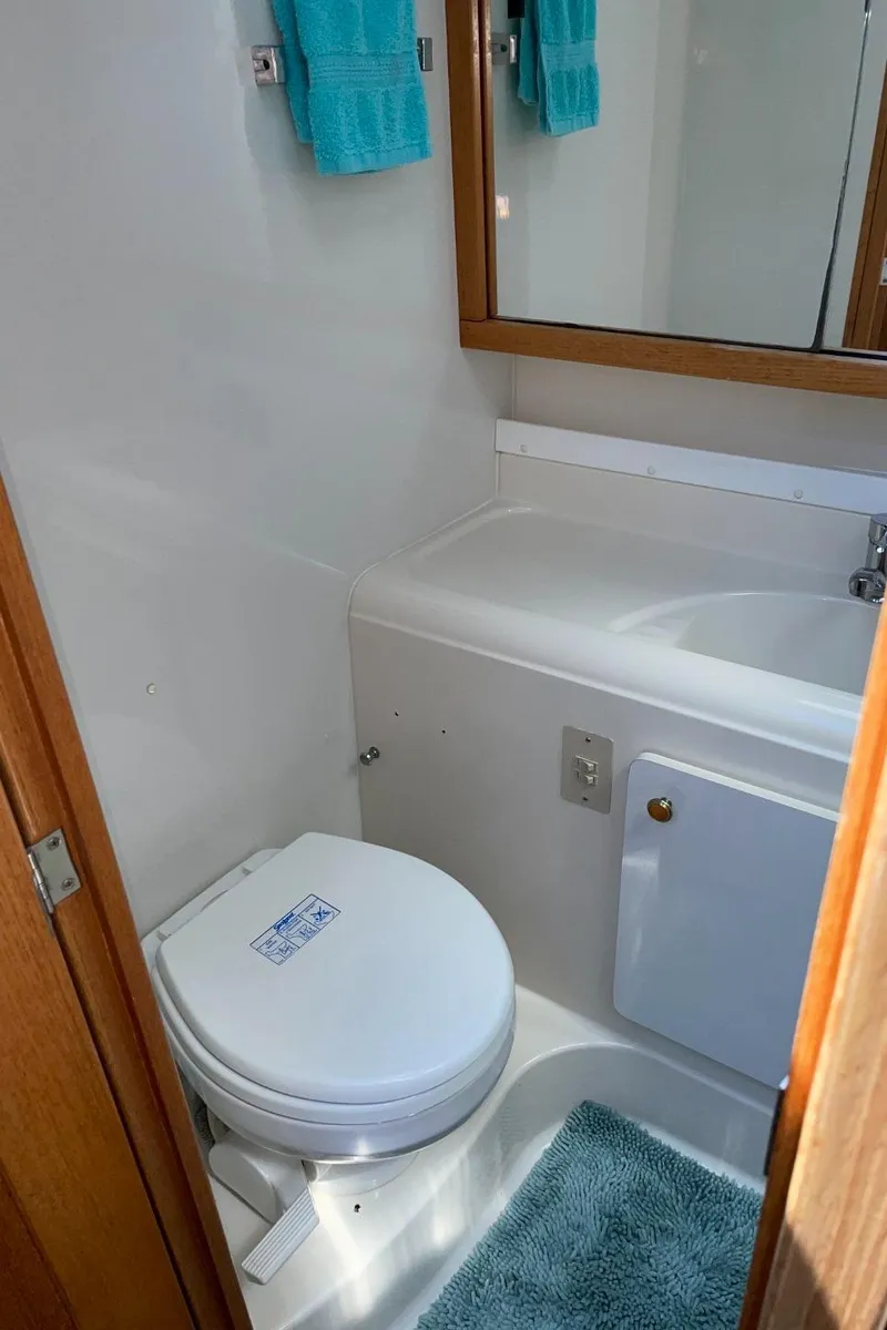 Slide: The Image of 1999 Bayliner 3388 Motoryacht bathroom with toilet, sink, mirror, and blue towels. - 41