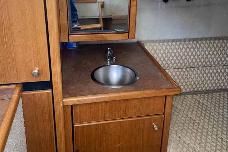 Slide: The Image of 1999 Bayliner 3388 Motoryacht interior sink area with wooden cabinetry and mirror. - 50