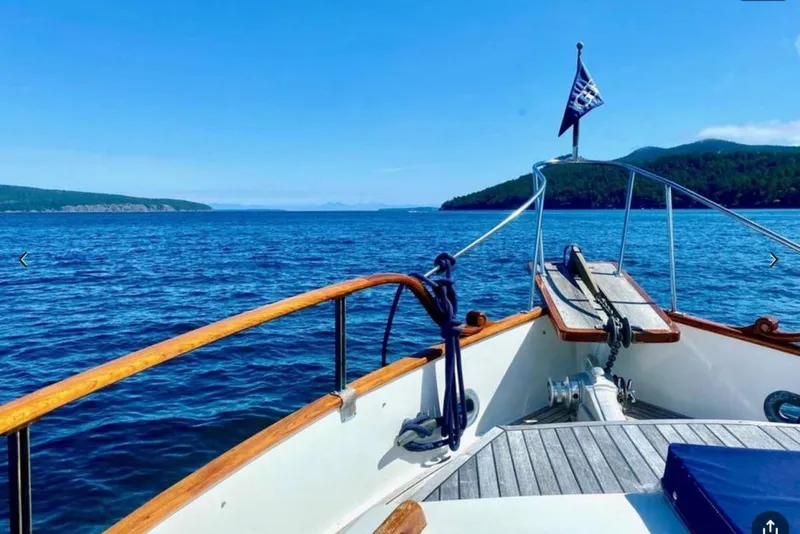 Slide: The Image of Bow view of 1984 Grand Banks 36 Classic yacht cruising on a clear blue sea. - 6