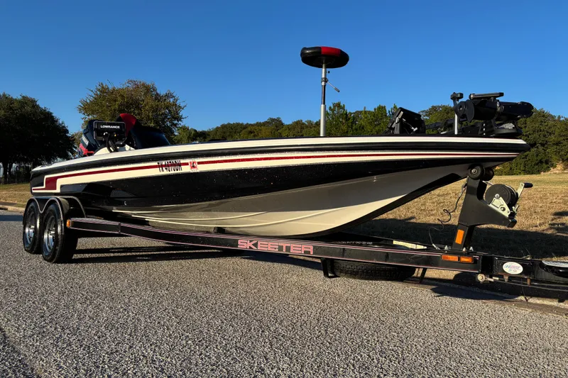 Slide: The Image of 2011 Skeeter ZX250 bass boat on trailer, parked outdoors under clear blue sky. - 1