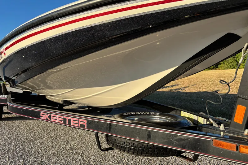 Slide: The Image of 2011 Skeeter ZX250 bass boat on trailer, parked near grassy area. - 11