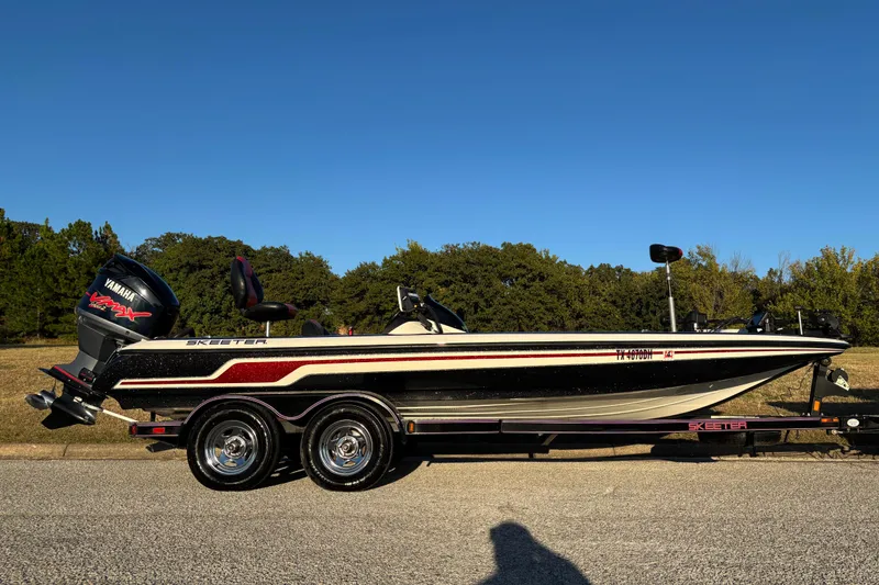 Slide: The Image of 2011 Skeeter ZX250 boat on trailer, parked outdoors under clear blue sky. - 2