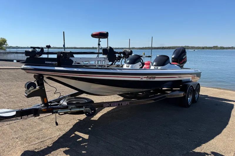 Slide: The Image of 2011 Skeeter ZX250 boat on trailer by a lake under clear blue sky. - 53