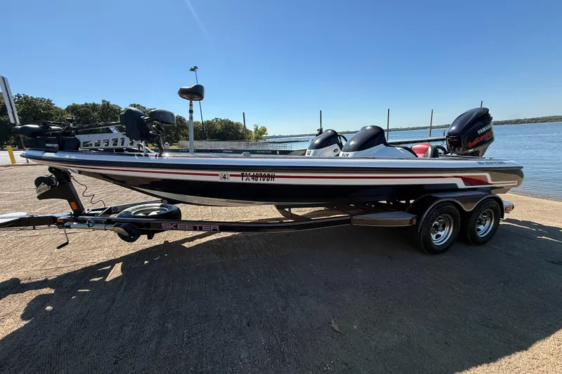 Slide: The Image of 2011 Skeeter ZX250 boat on trailer by lake, clear sky background. - 55