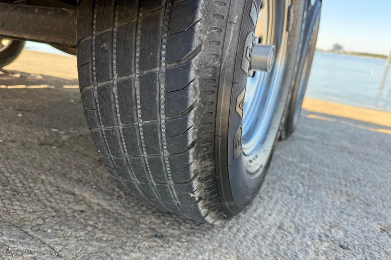 Slide: The Image of Close-up of a 2011 Skeeter ZX250 trailer tire on a concrete surface by water. - 57