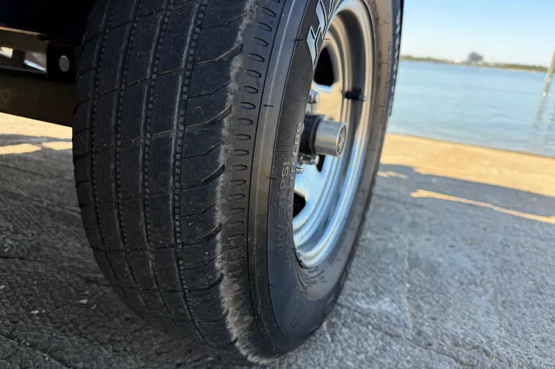 Slide: The Image of Close-up of a 2011 Skeeter ZX250 trailer tire by a waterfront. - 58