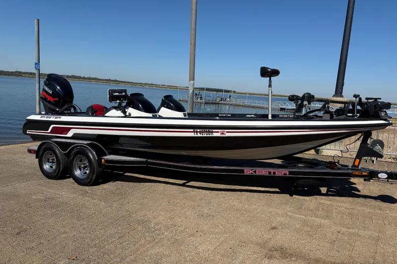 Slide: The Image of 2011 Skeeter ZX250 boat on trailer by a lake, featuring Yamaha engine. - 68