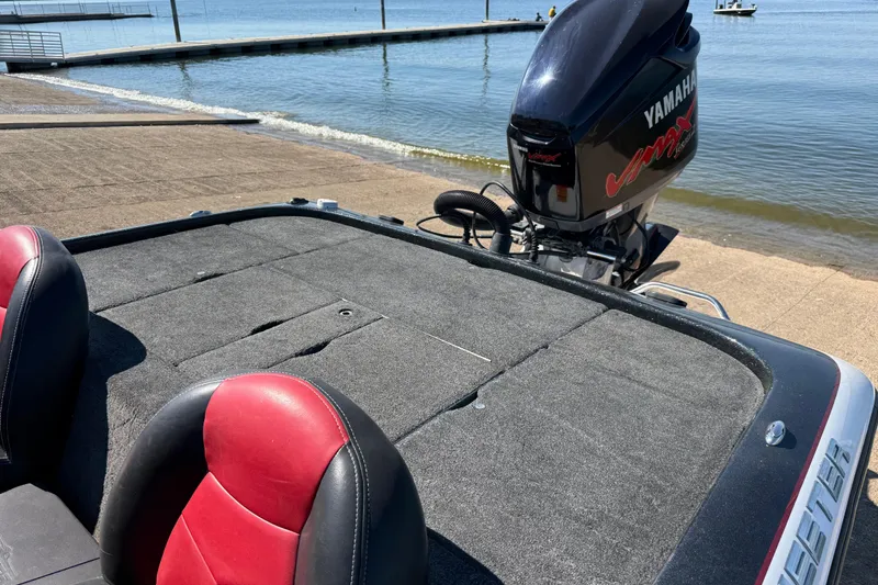 Slide: The Image of 2011 Skeeter ZX250 boat with Yamaha engine, red and black seats, near a lakeside dock. - 77