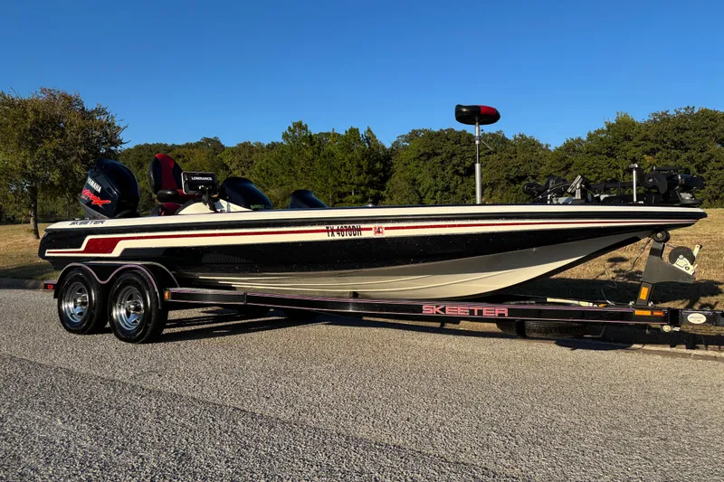Slide: The Image of 2011 Skeeter ZX250 boat with Yamaha engine, red and black seats, in grassy area. - 8